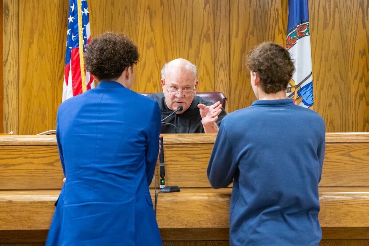 Professor Jeff Harding, serving as the presiding judge, speaks to two students during a mock trial scrimmage.