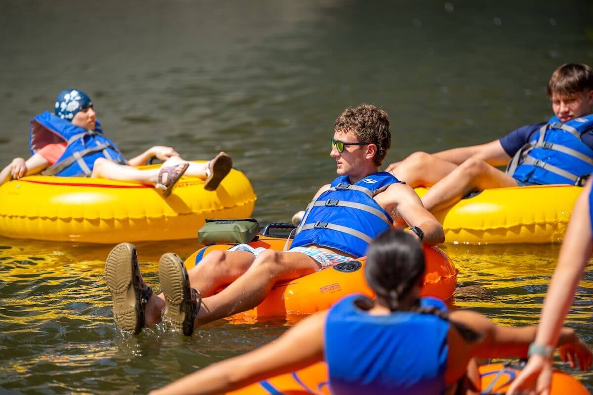 Students wearing blue PFDs float in tubes on the Shenandoah River.