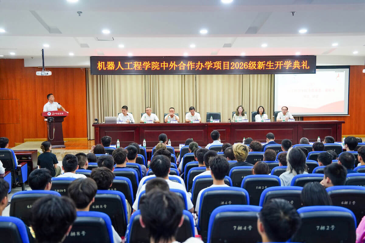 Administrators from Yangtze Normal University and Shenandoah University sit at a dais in front of a room full of students.